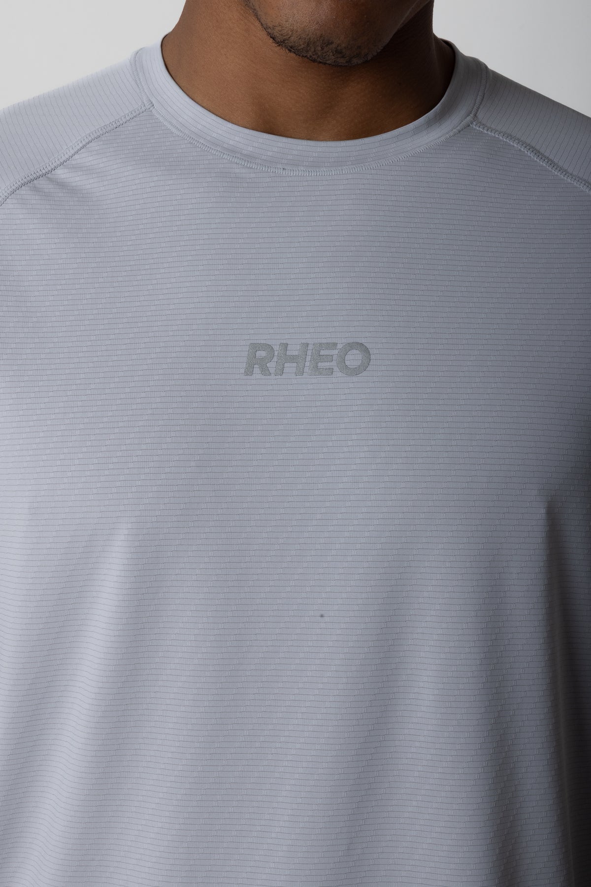 Close-up of RHEO CryoSilk™ T-Shirt in grey for men's padel, showing the lightweight textured fabric and chest logo.