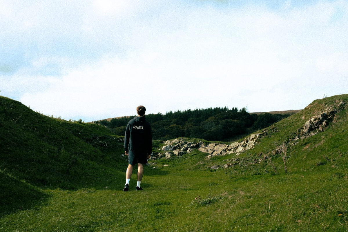 Athlete from behind in RHEO kit, walking into a Peak District valley