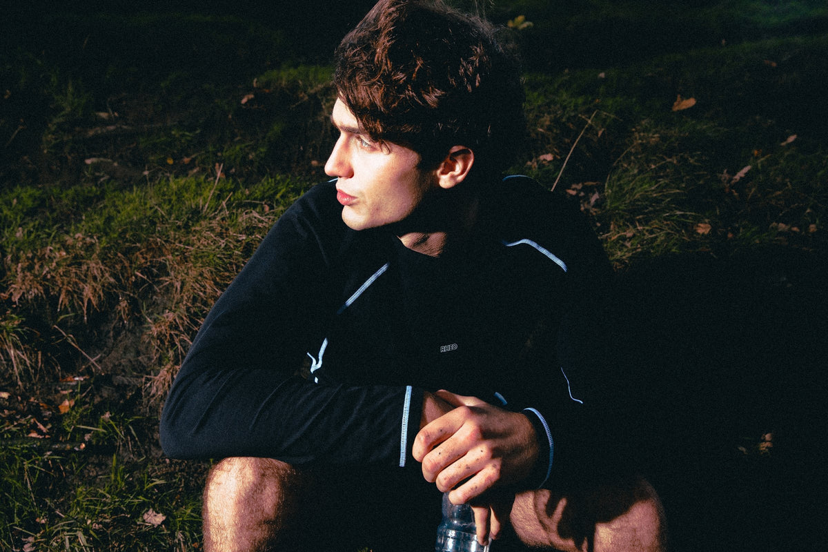 Athlete resting on a dark hillside in a CryoSilk long sleeve