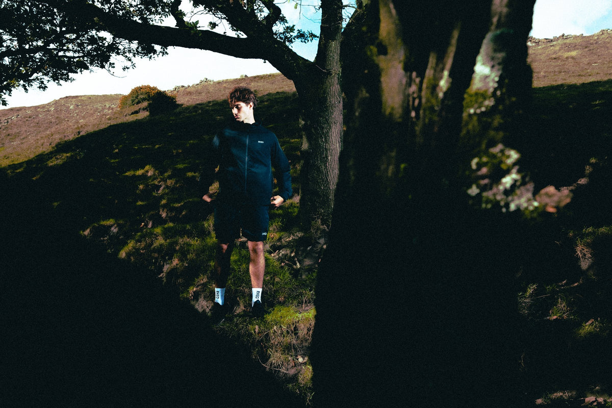 Athlete standing in deep shade under a hillside tree