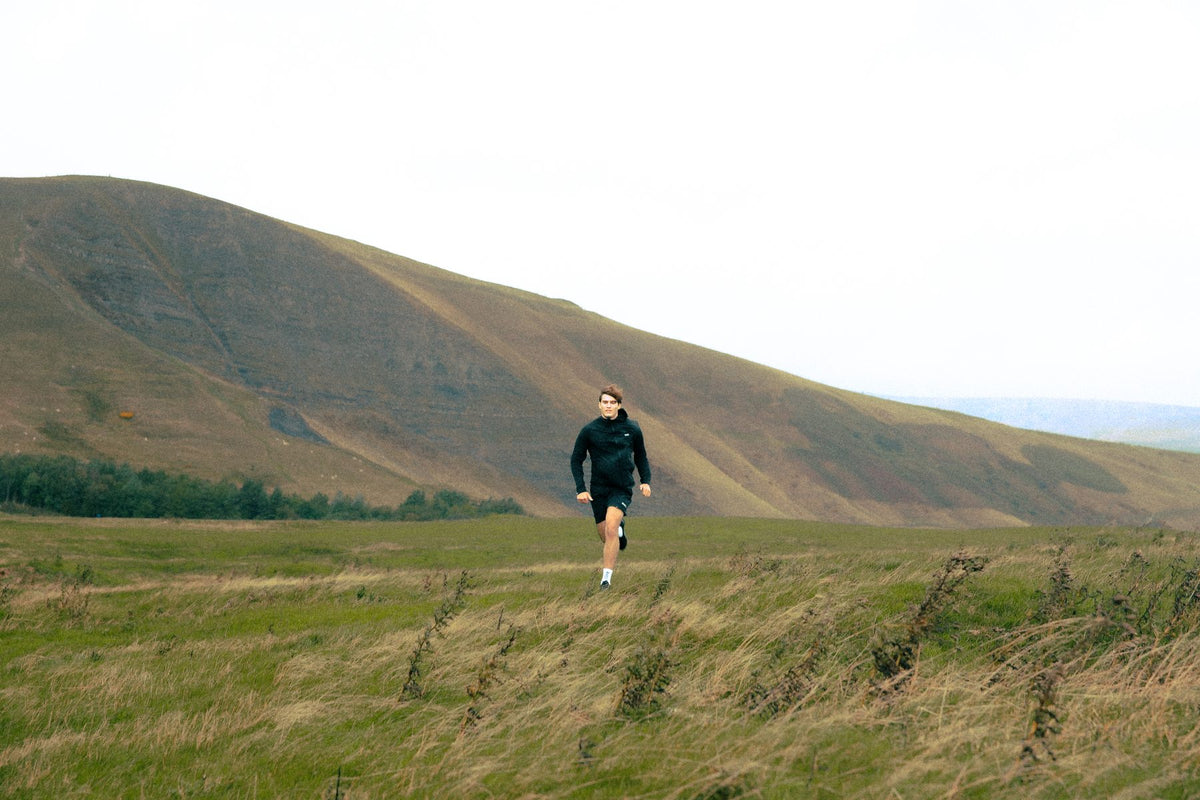 Runner in black ClayShell shorts crossing open Peak District moorland